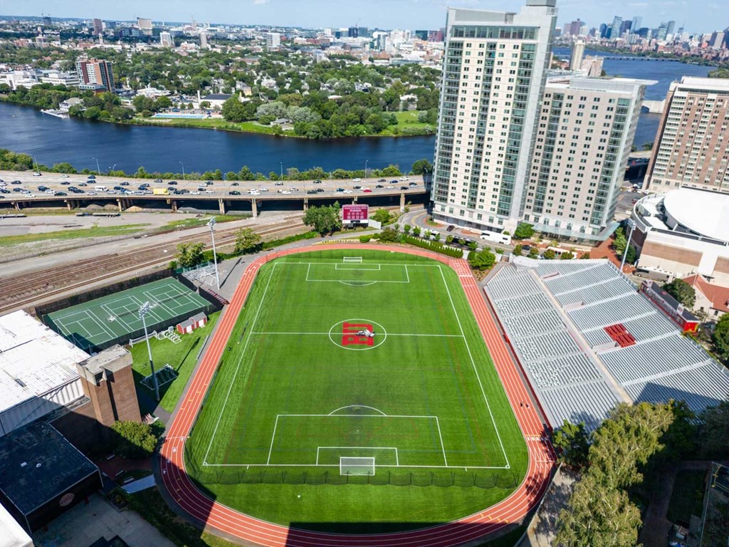 an aerial view of a soccer field in a city with a river